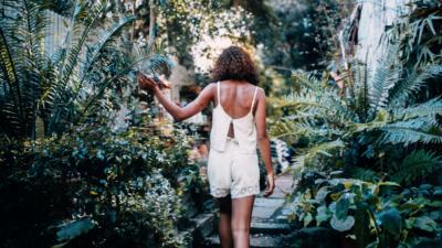 Girl walking through plants on a patio